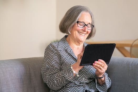 Happy senior woman with gray hair using a tablet at home, enjoying technology.